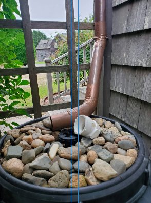 All it takes to collect rainwater for irrigation is a downspout, a 55-gallon plastic drum, stones and a screen for filtering.