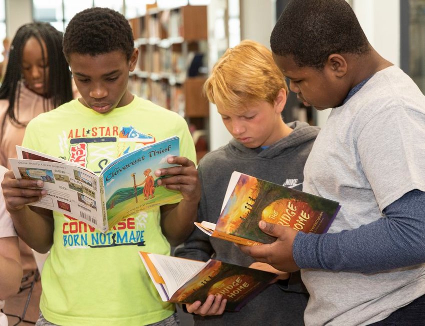 From left, Akeel Walker, Tyler Miller and Dakara Turner with Padma Venkatraman's books in the Cyrus Peirce School library this week. Venkatraman will visit the school to speak with students Tuesday.