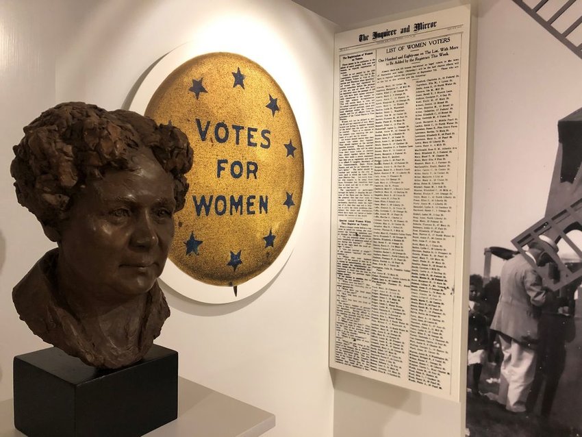 A bust of Elizabeth Cady Stanton, a Women's Suffrage Association pin and a copy of The Inquirer and Mirror with a list of women voters on display in the Nantucket Historical Association's &amp;#8220;Abolition to Suffrage&amp;#8221; exhibit.
