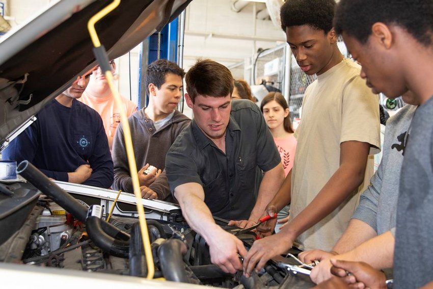Nantucket High School automotive teacher Derek Mulson, left, works under the hood of a car with students Tuesday.