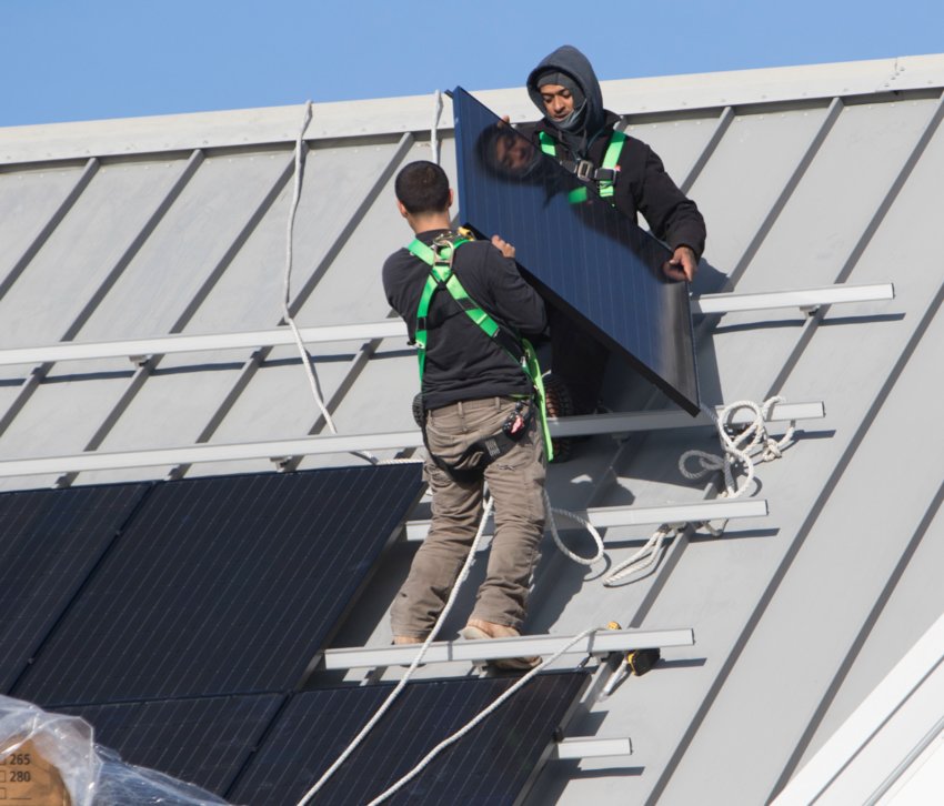 Workmen install solar panels on the roof of the Nantucket Ice rink off Backus Lane.