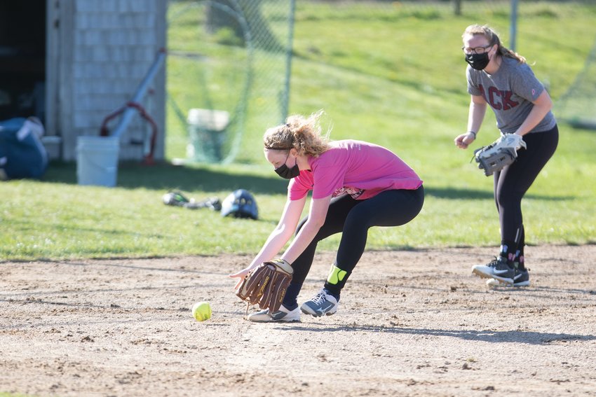 Maclaine Willett (in pink) fields a ground ball with Melanie Bamber looking on