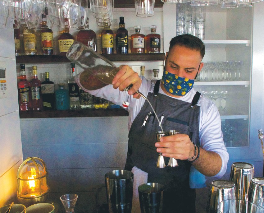 Conrad Meurice pours a cocktail behind the renovated bar at Bar Yoshi.