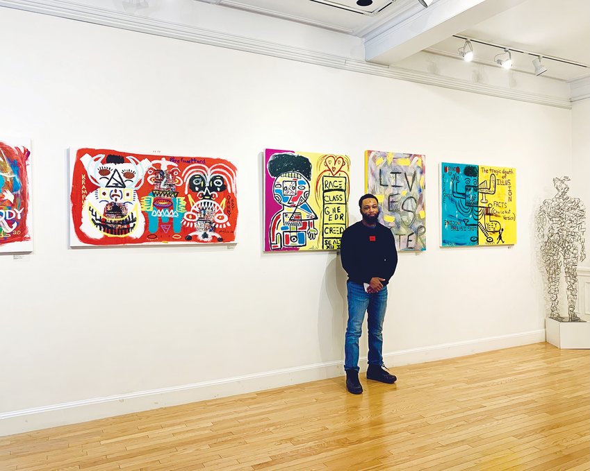 Halim Flowers in front of a wall of his artwork at the DTR Modern Gallery on Newbury Street in Boston.