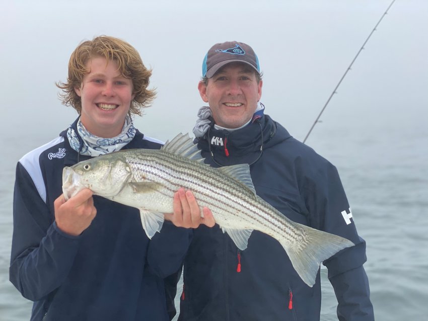 Tuck and Davey Jay with a striped bass they caught this week.
