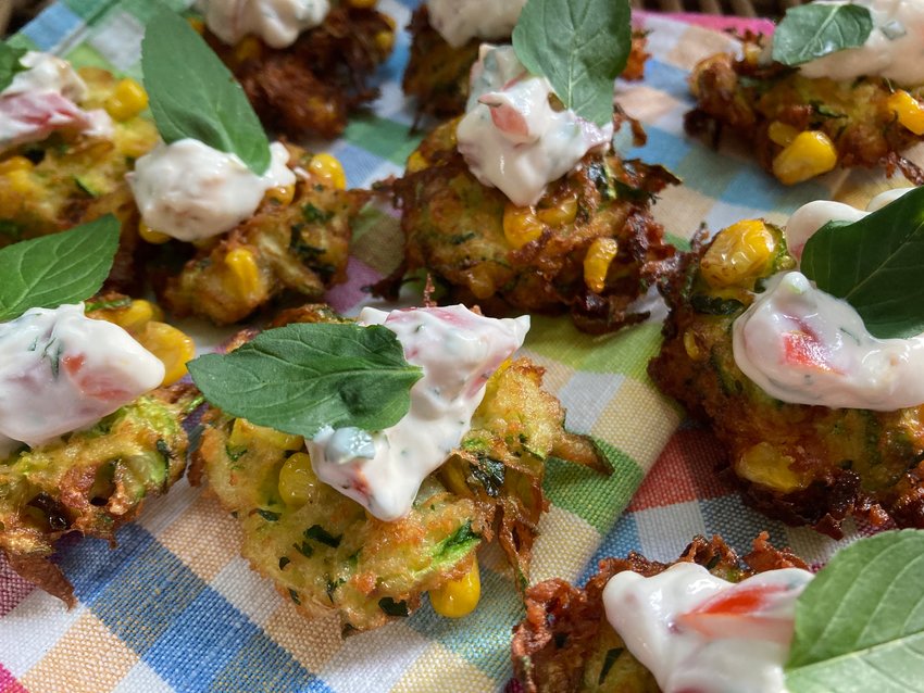 These corn and zucchini fritters are topped off with a dollop of cherry tomato and sour cream dip.