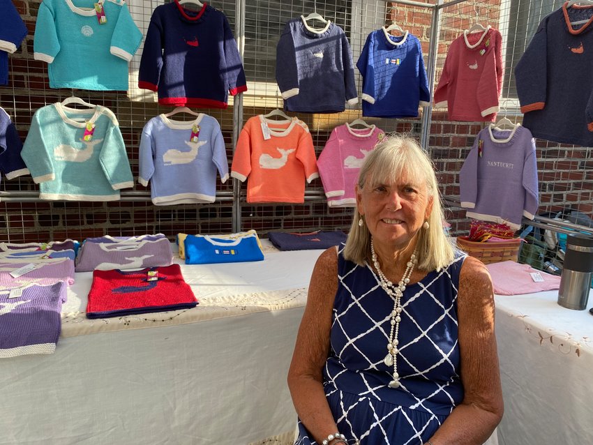 Sarah Wright, who spent 24 years in the U.S. Air Force, with her hand-knitted children&rsquo;s sweaters at the Nantucket Farmers &amp; Artisans Market.