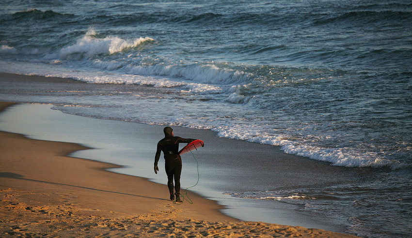 Jeremy Norwood, of Nantucket, carries his board as he heads for the surf at Cisco Beach in March.
