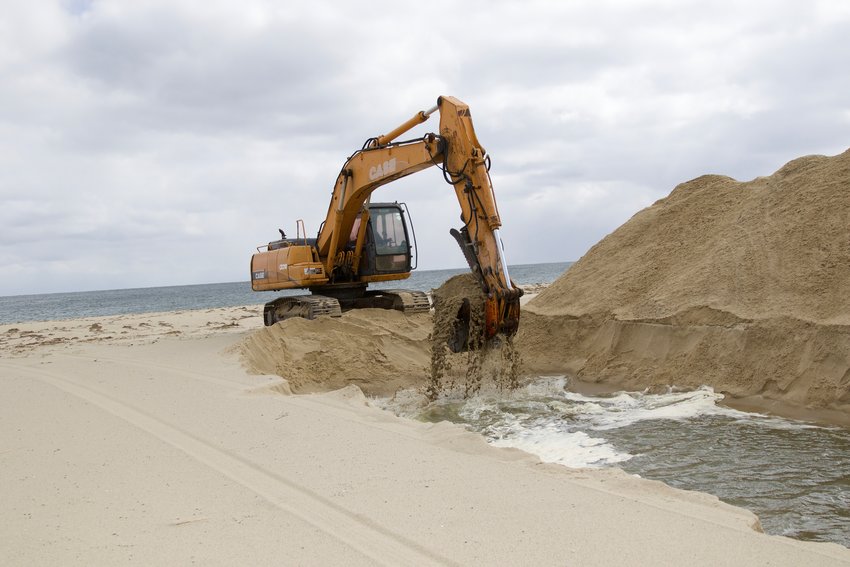 An excavator from AH Construction opens Sesachacha Pond to the ocean Monday.