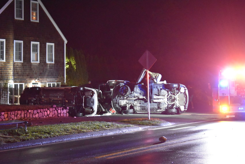 A Nantucket police officer and Massachusetts Army National Guard member work to remove the driver of a rolled over vehicle involved in an Old South Road crash Tuesday night.
