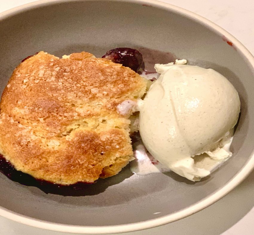This sweet polenta dark cherry grunt is a cobbler-type dish accompanied by vanilla bean ice cream.
