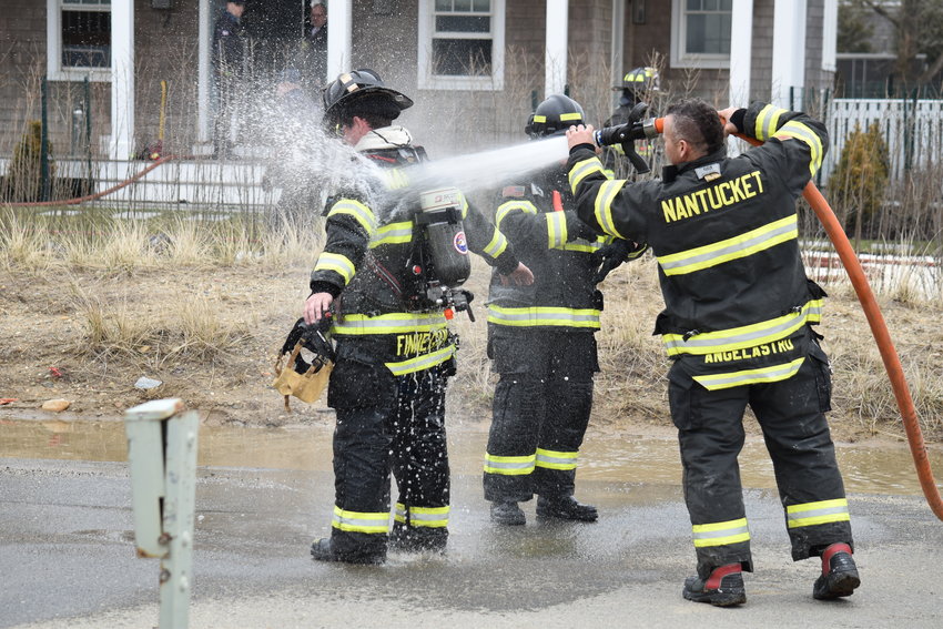 Firefighters get hosed down at the scene of a possible explosion in the basement of a Sconset home Thursday.