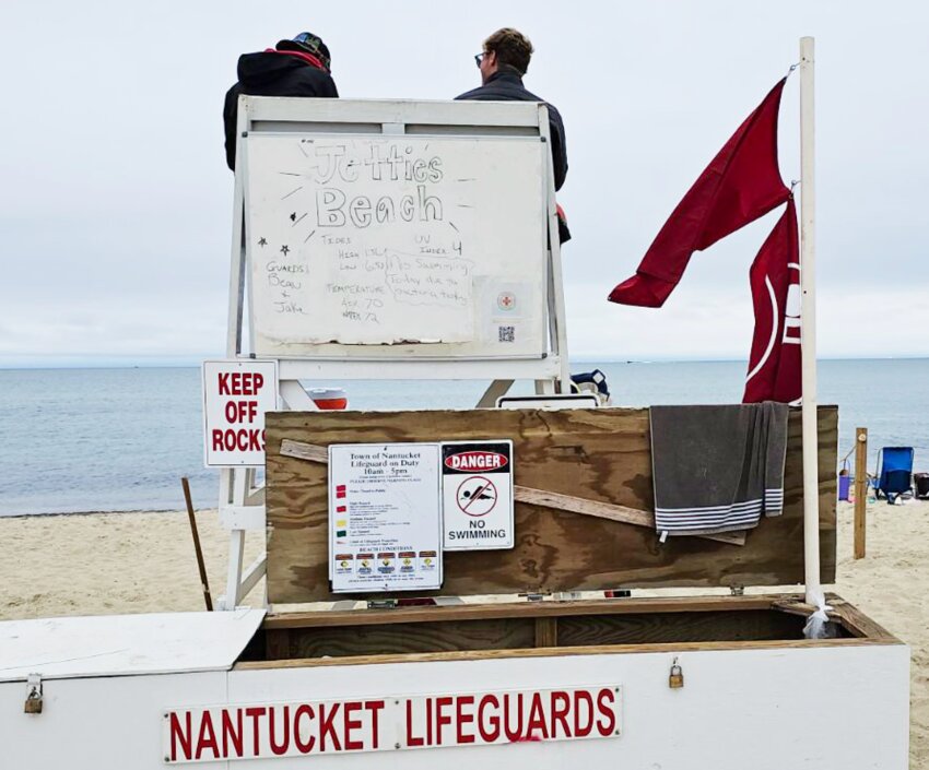 Red flags fly on the lifeguard stand at Jetties Beach Thursday, which was closed to swimming due to high bacteria counts.