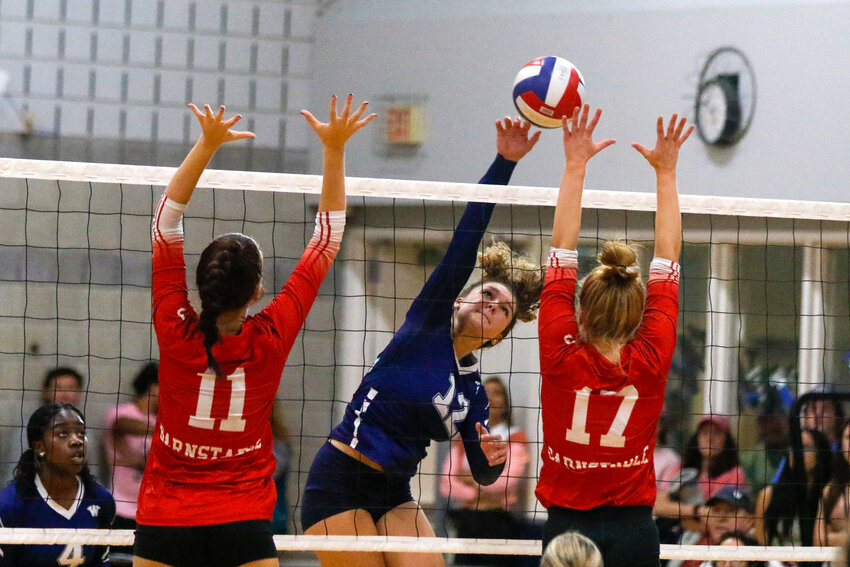 Chloe Marrero tips the ball over a pair of Barnstable blockers during a 3-0 loss Monday.