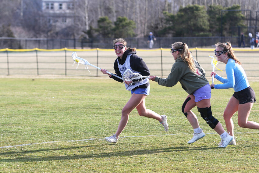 From left, Myah Johnson carries the ball away from Alex Wisentaner and Evy Stahl at girls lacrosse practice last Monday.