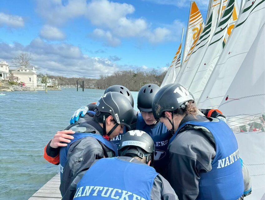 Junior captain Rory Murray (center back) and senior captain Archie Ferguson (center front) give a pep talk in the huddle before competing in the Greenwich Super Saturday regatta.
