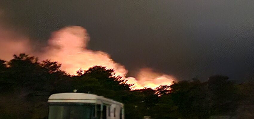 The glow of flames from a two-acre brush fire fills the night sky over Old South Road Tuesday.