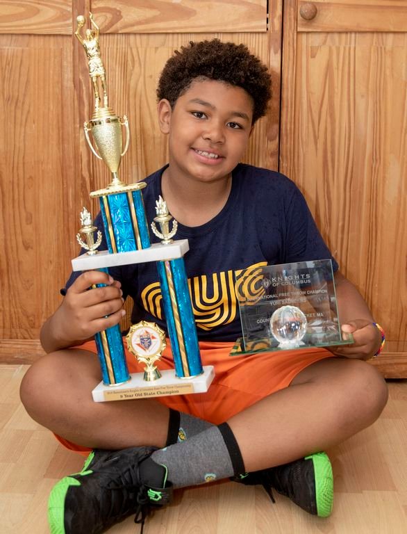 Yuri Saunders, 9, holds his trophies for winning the Knights of Columbus International Free Throw Championship in his age group.
