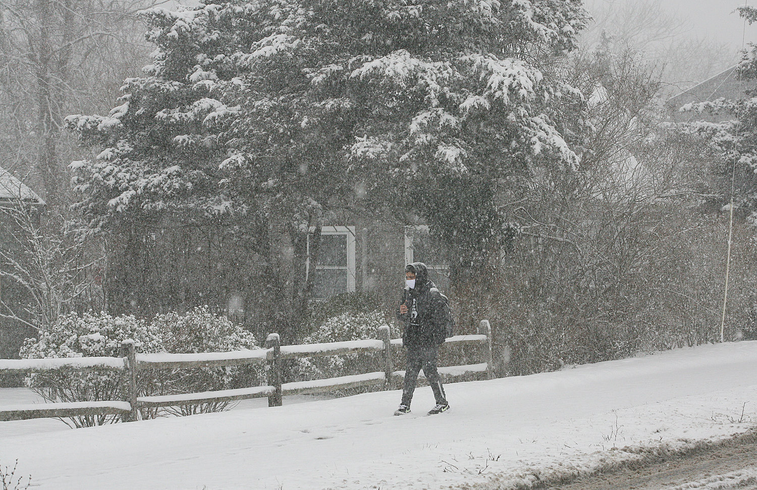 A person, mask on, makes his way through the snow along Surfside Road near the schools.