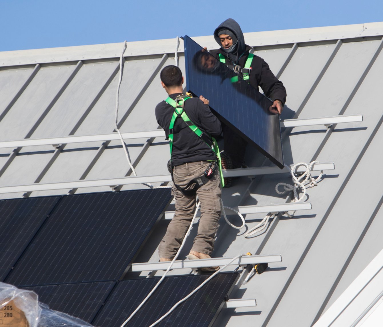 Workmen install solar panels on the roof of the Nantucket Ice rink off Backus Lane.