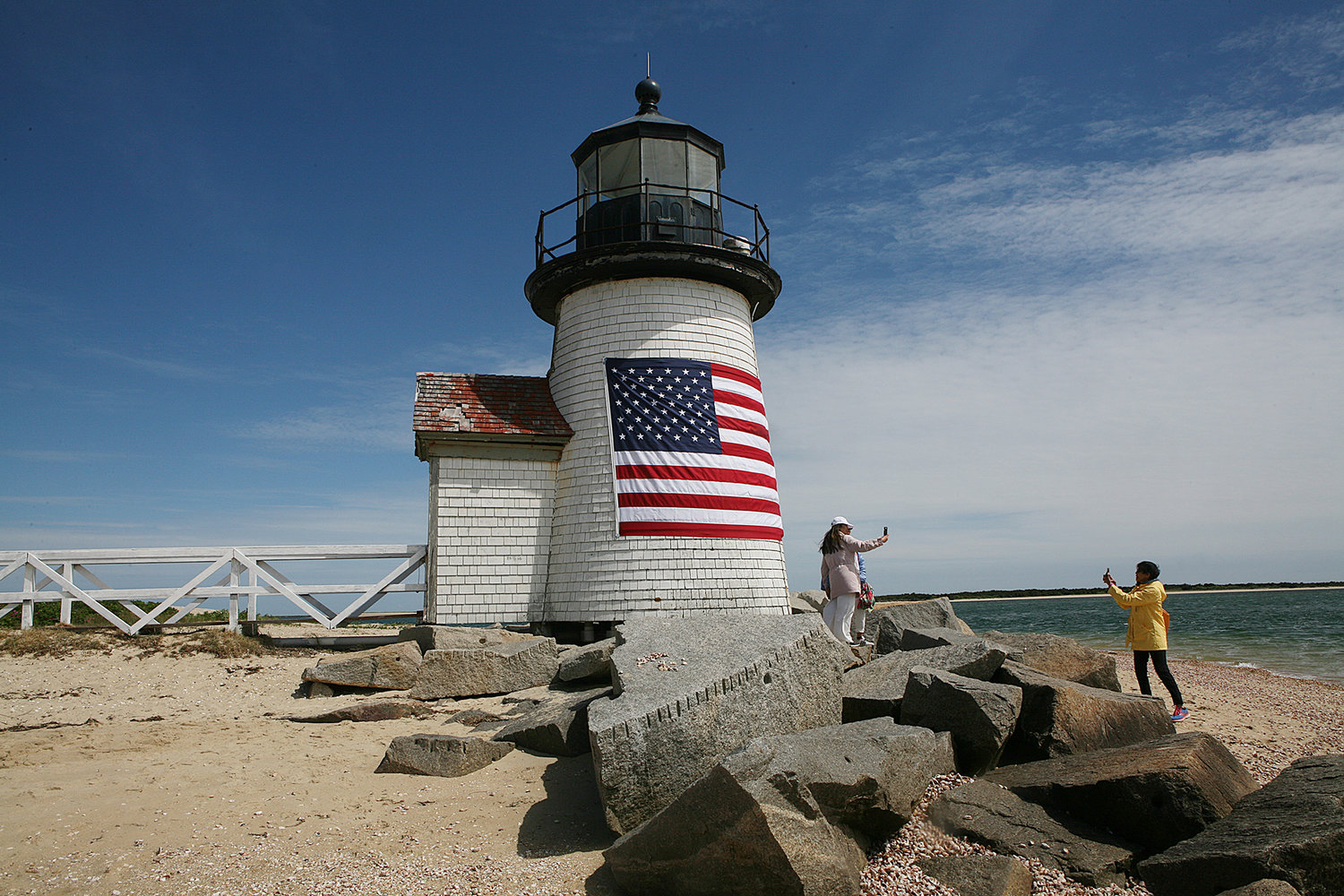 People take photos after a crew from the US Coast Guard Station Brant Point took down the daffodil wreath and replaced it with a flag in honor of Memorial Day and the Fourth of July at the Brant Point lighthouse