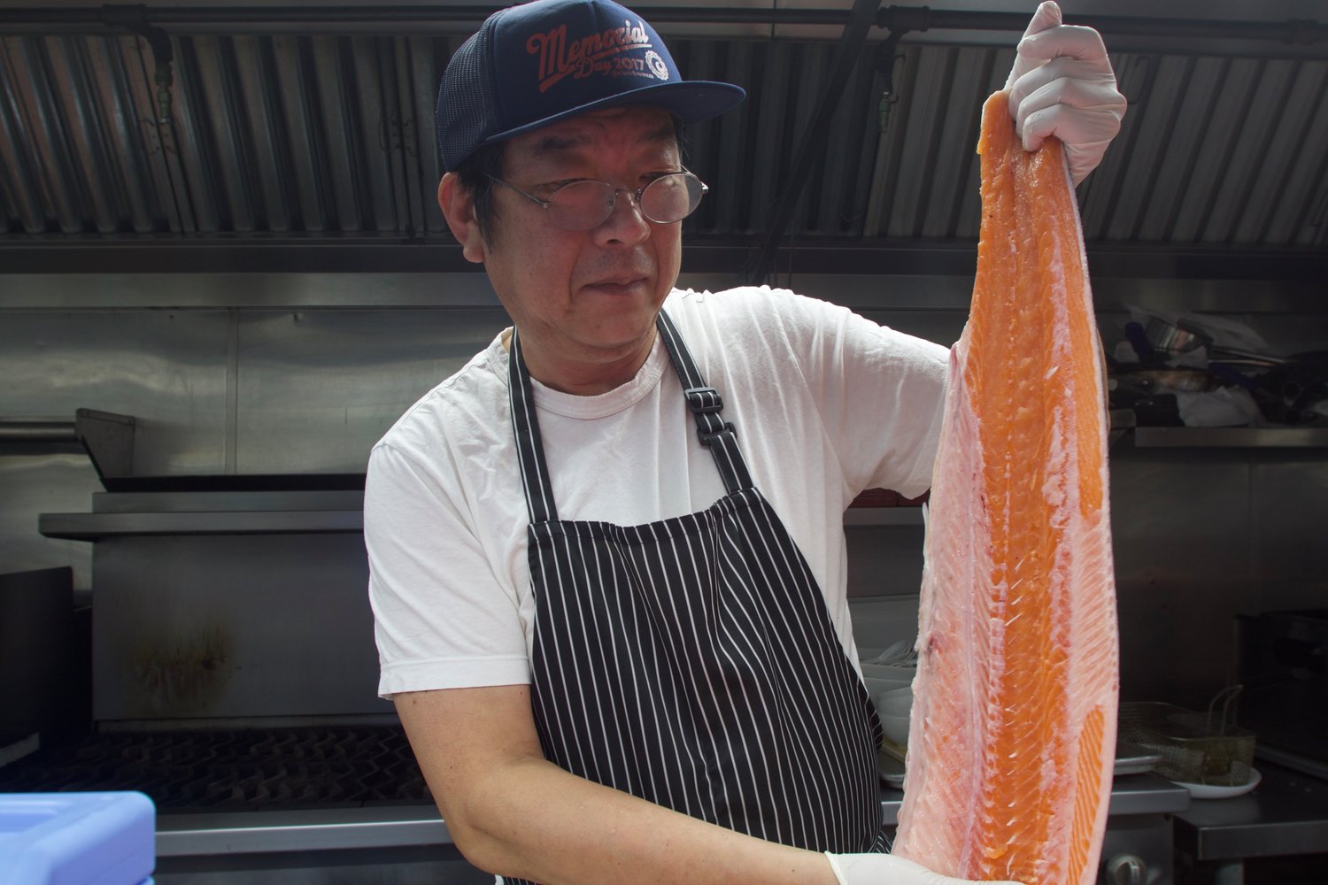 Ide cutting into a three-foot salmon with a Japanese-style chef’s knife made specifically for taking the spine off a fish.