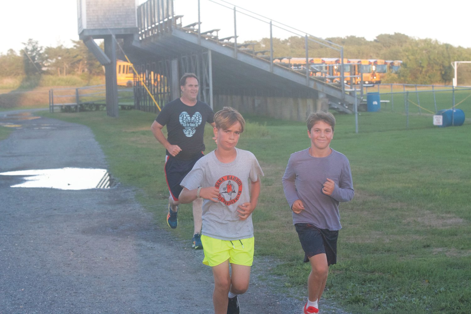 Coach Phil Allen follows Tavio Gomes, left, and Burke Lombardi around the football field during cross-country practice last Thursday.