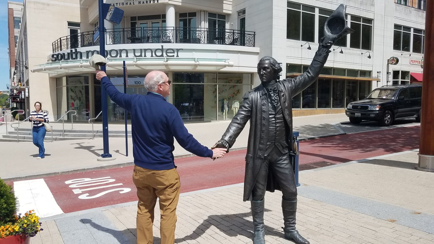 Philbrick holding hands with a statue of Washington in Alexandria, Va.