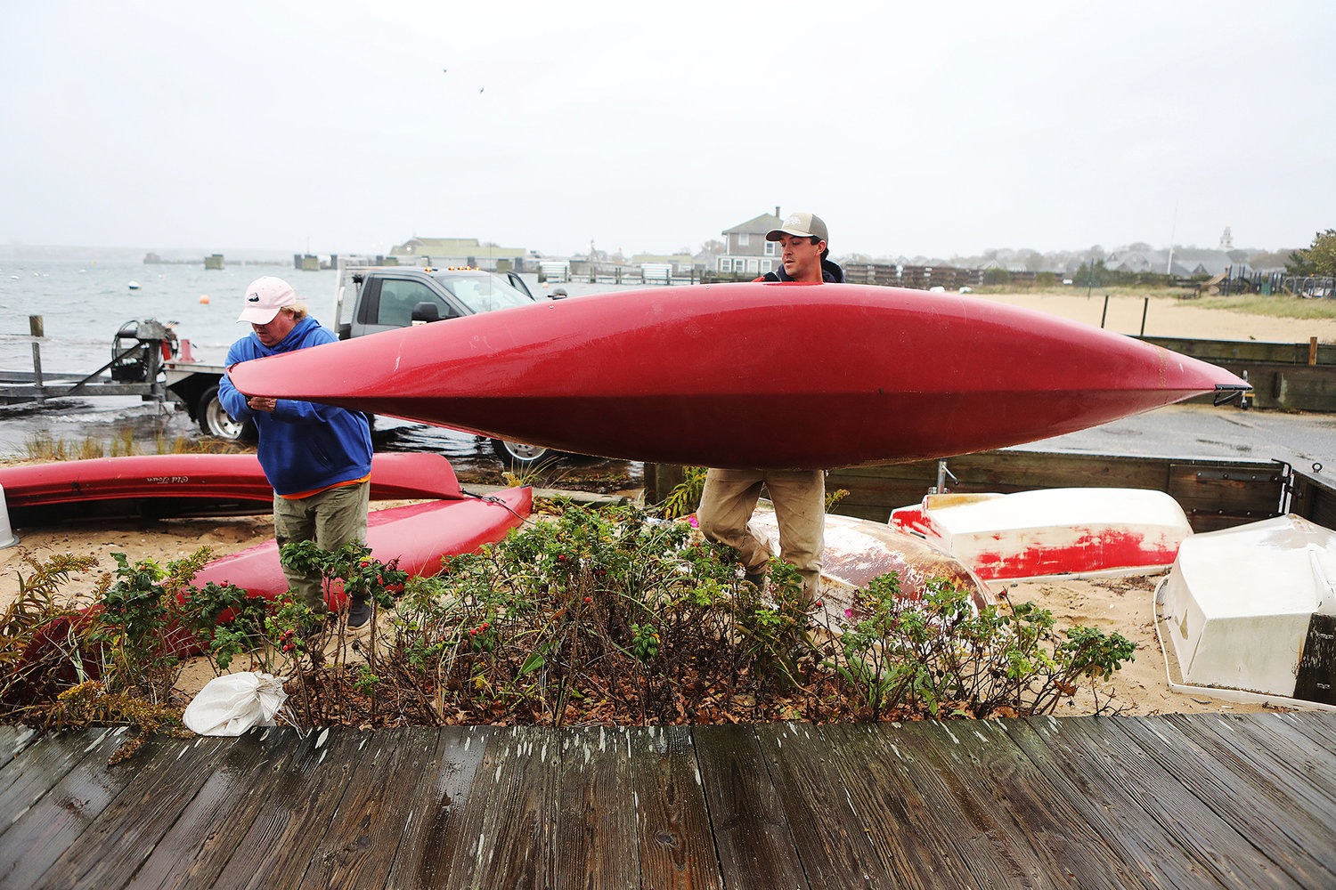 Harbormaster Sheila Lucey (left) and assistant harbormaster Shane Carey move a kayak away from the storm-driven high tide at the Children's Beach boat ramp Tuesday afternoon.