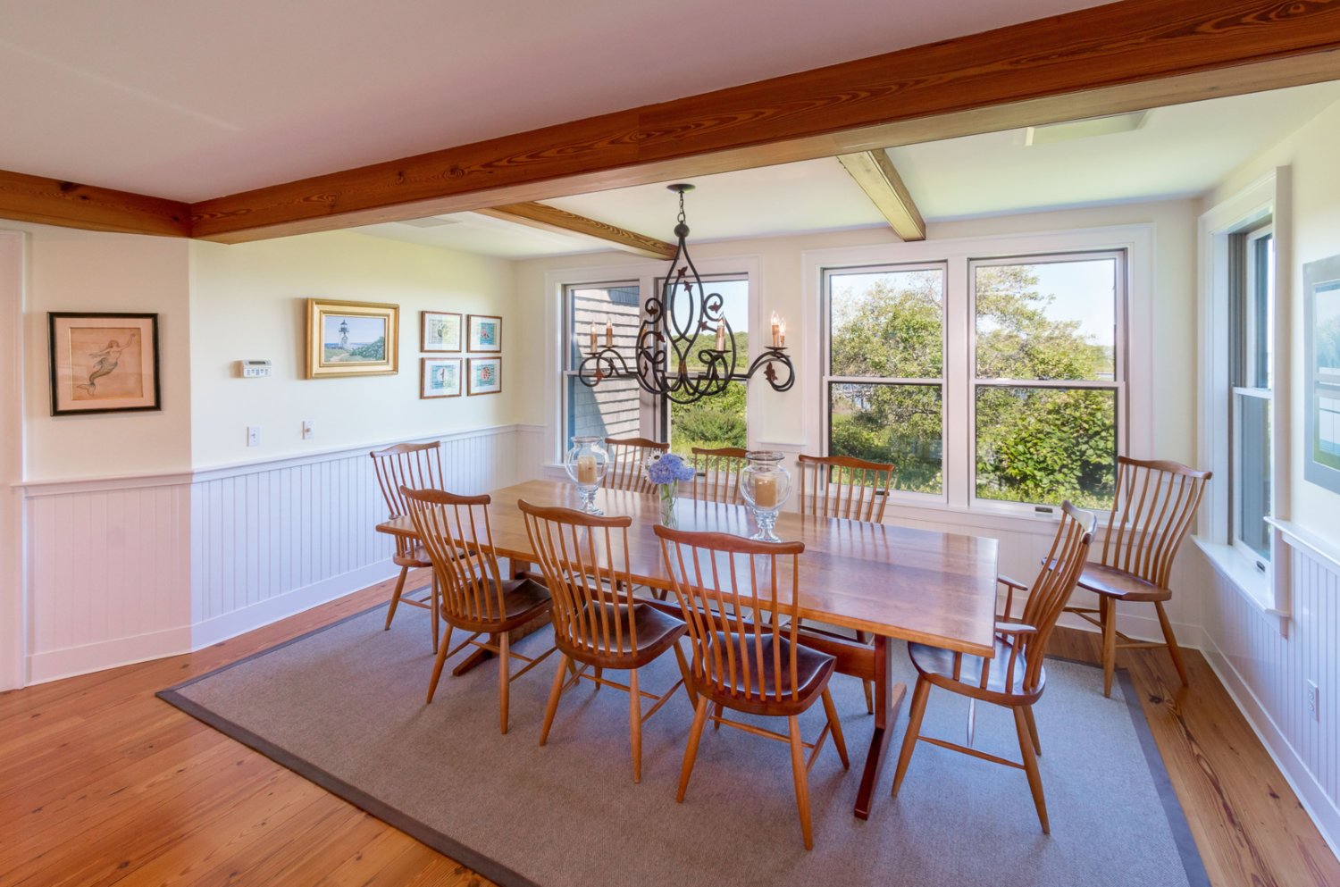 The dining area has an exposed-beam ceiling and multiple windows with views of Polpis Harbor.
