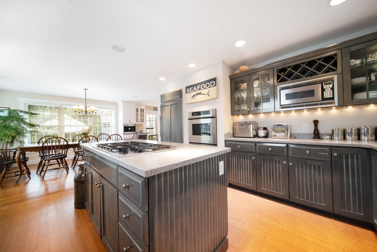 The open kitchen has a central island with cooktop, multiple cabinets for storage, a pantry and high-end appliances by Sub-Zero and Thermador.