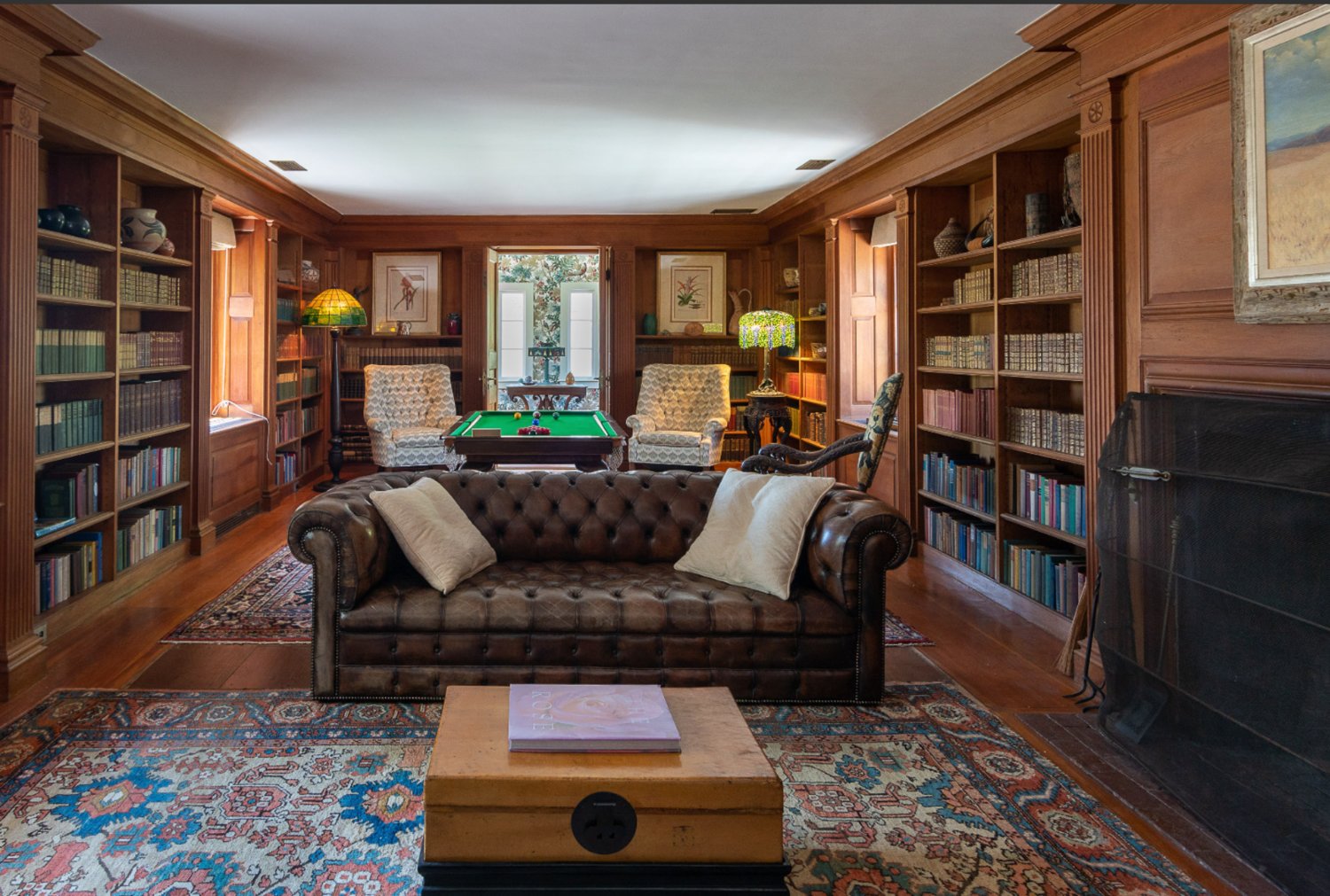 The second-floor library and game room has a fireplace and built-in shelving.