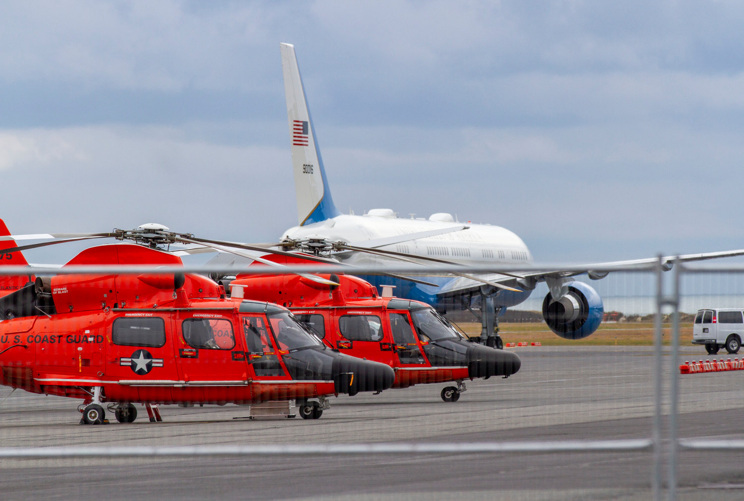 Air Force One on the tarmac of Nantucket Memorial Airport with a pair of U.S. Coast Guard helicopters in the foreground.