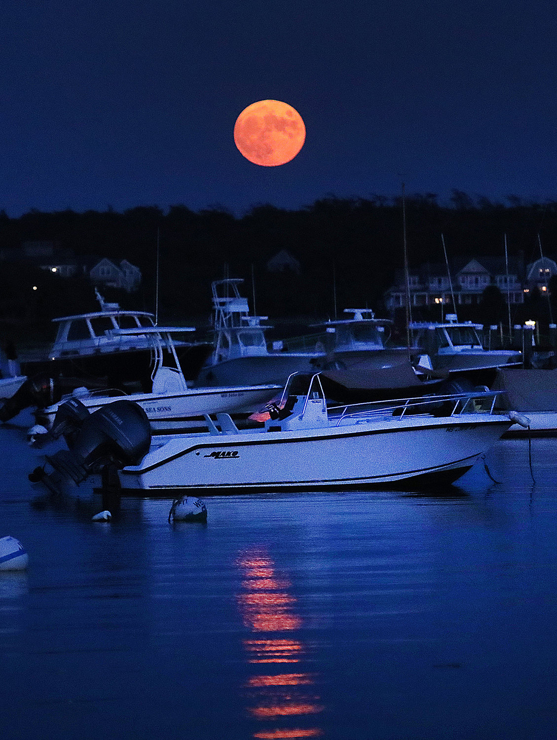 The full moon rises over boats moored in the harbor on July 23. The July full moon is known as the Thunder Moon or the Buck Moon.