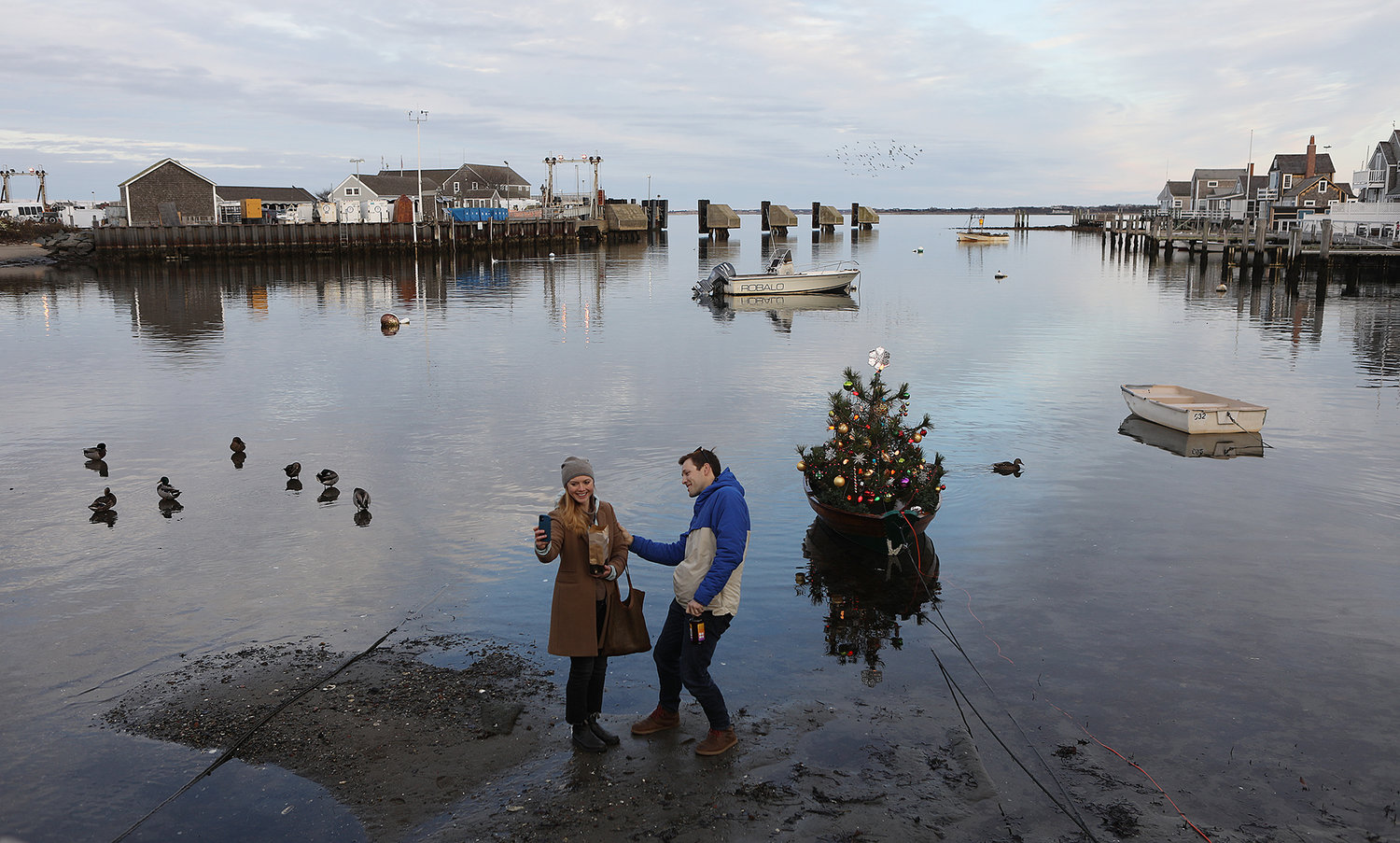 A couple takes a selfie with the iconic Christmas dory along Old North Wharf on Stroll weekend.