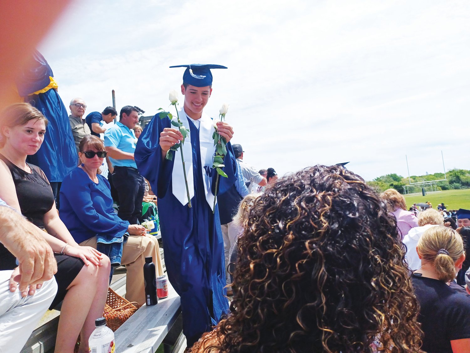 Hudson Perry carries two white roses through the bleachers during Saturday’s Nantucket High School commencement exercises.