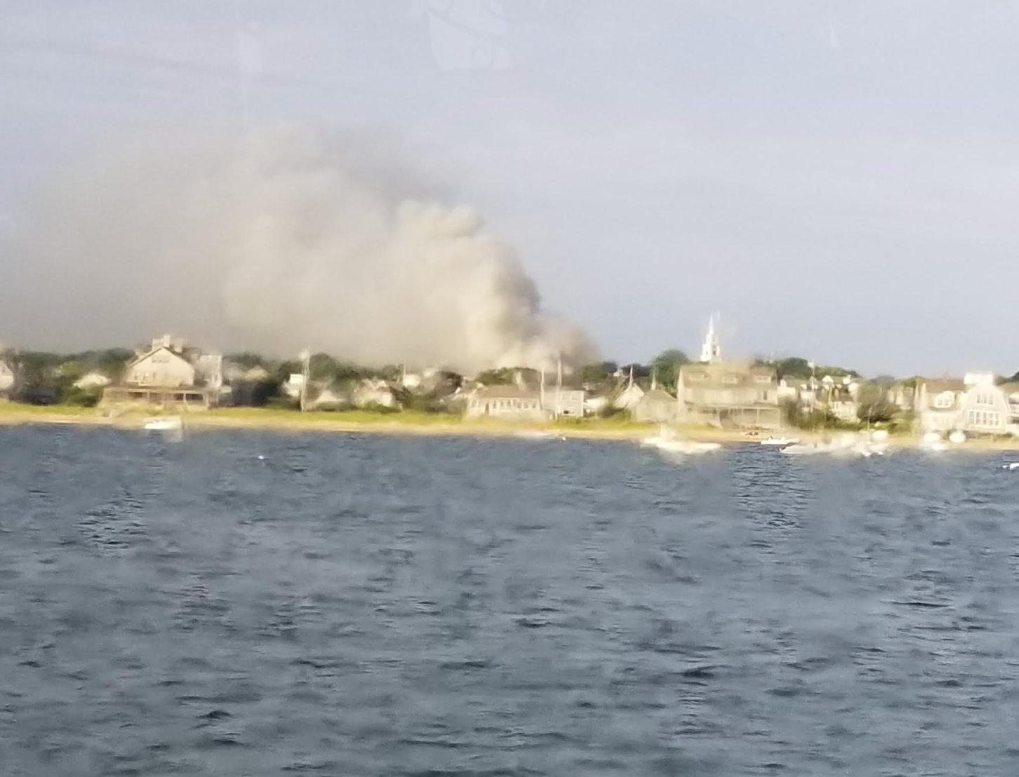 Smoke rises over the island as seen from the fast ferry Grey Lady heading into the harbor Saturday morning.