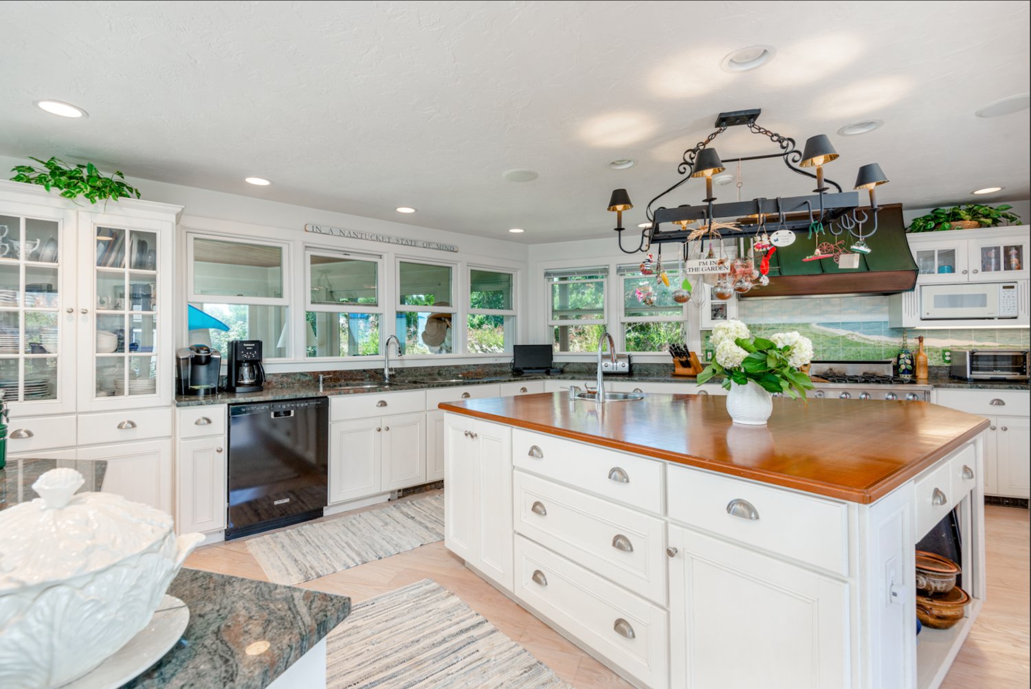 The spacious gourmet kitchen has granite countertops, a wood-topped center island with sink, and high-end appliances by Sub-Zero and KitchenAid.