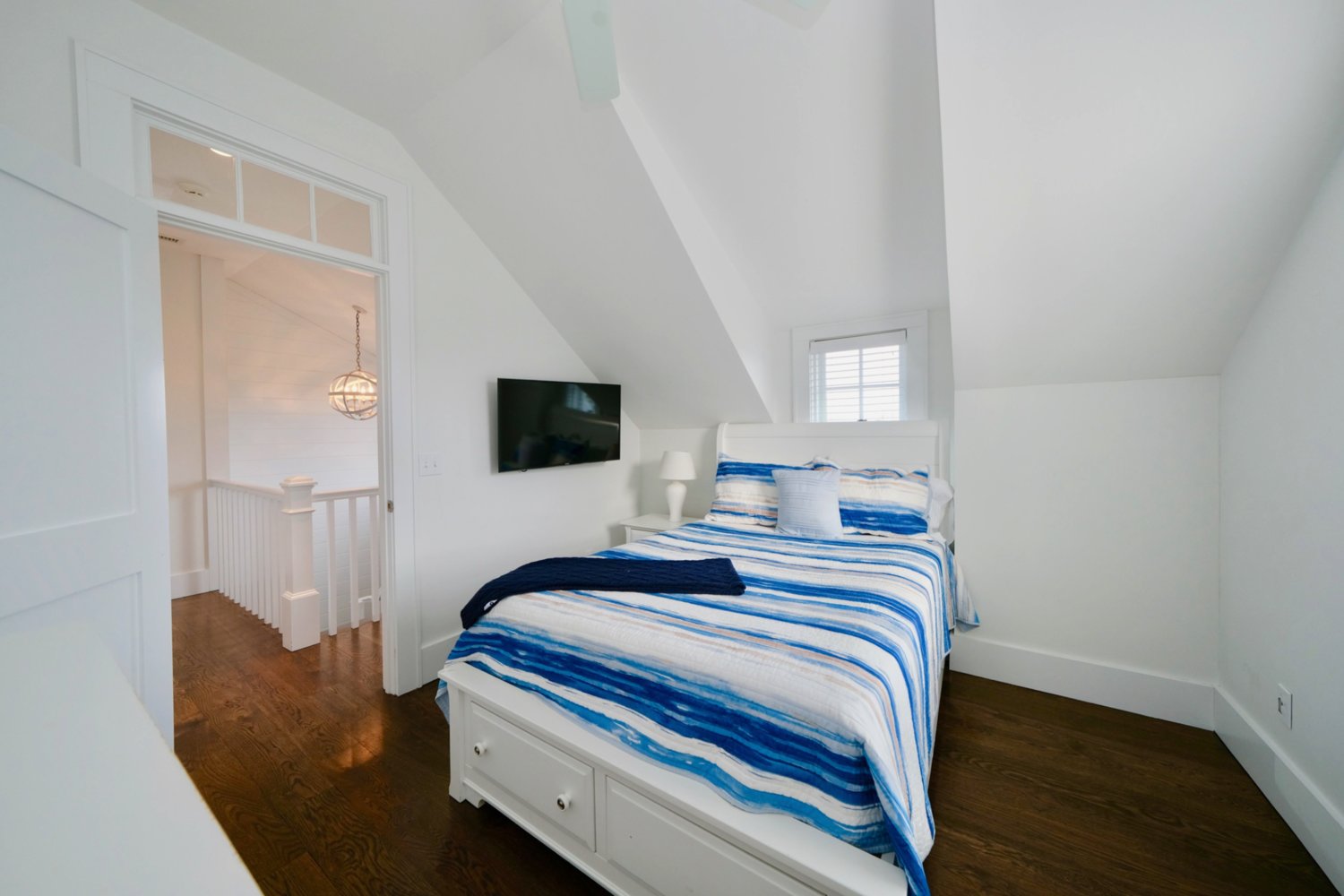 This second-floor bedroom has wood floors and a vaulted ceiling.
