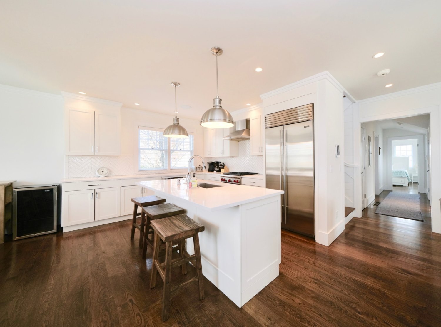 The gourmet kitchen has wood floors, a large center island with a sink and bar-style seating, and high-end appliances including a Wolf cooktop and range.
