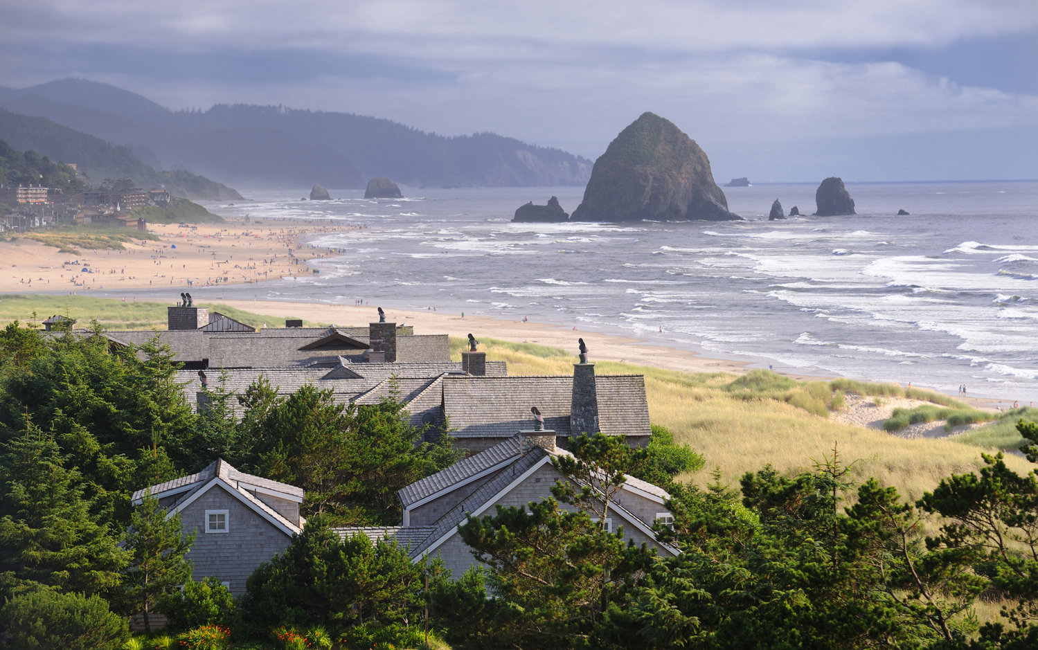 The famous Haystack Rock on Cannon Beach, Ore., with an incredible cloudscape building up on the horizon as the mist of the waves sprays over beach-goers.