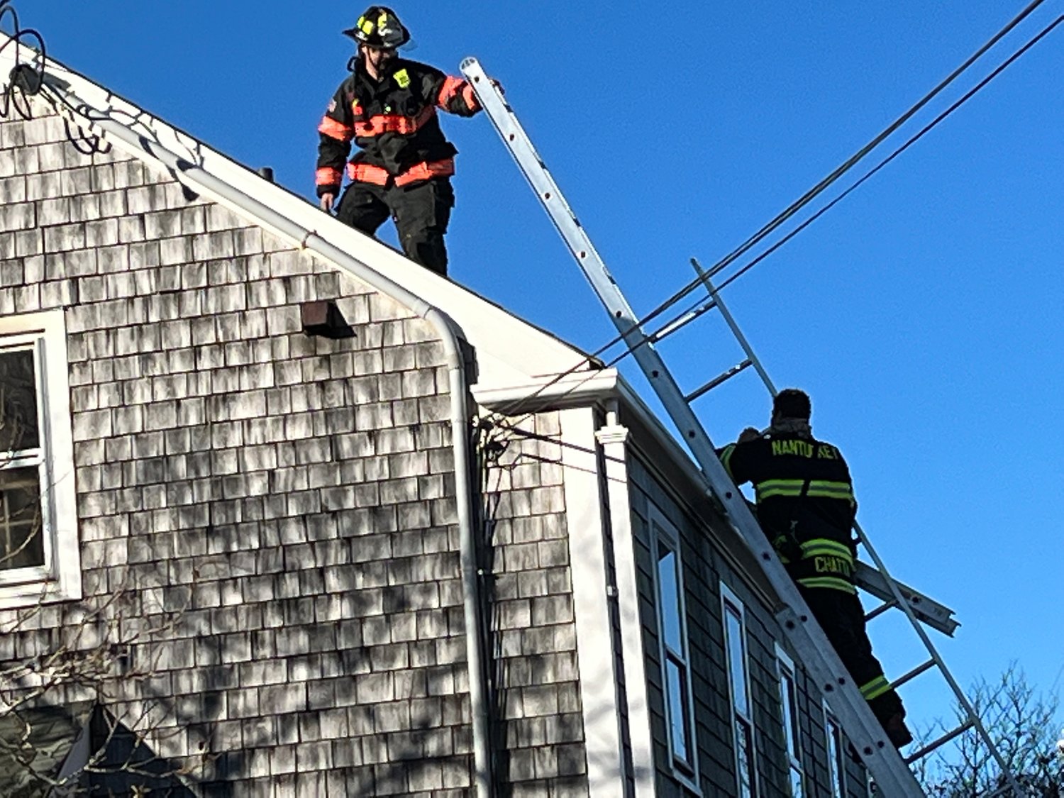 Firefighters climb down from the roof of 32 Vestal St.