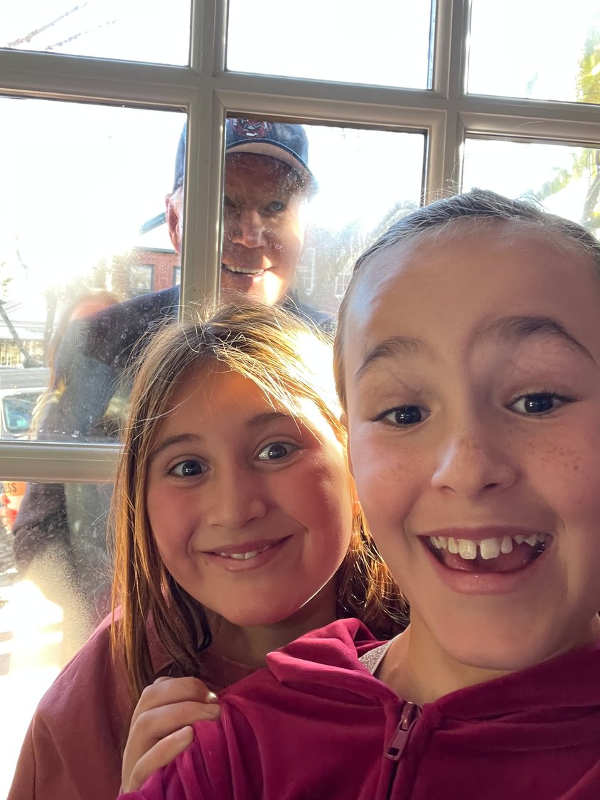 Eve Rios and Abby Kane take a selfie with President Biden in the background at Lemon Press Saturday.