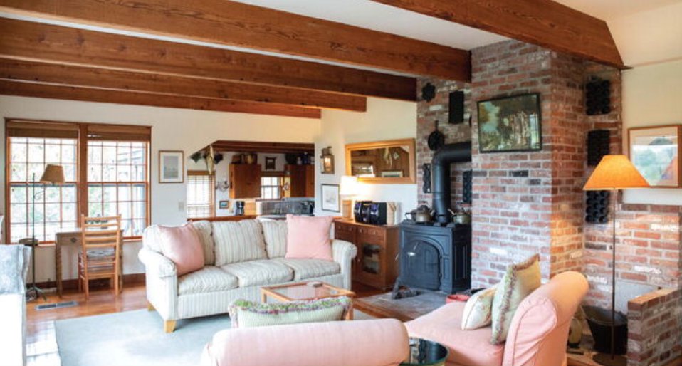 The living room in the main house has exposed beams and a wood stove.