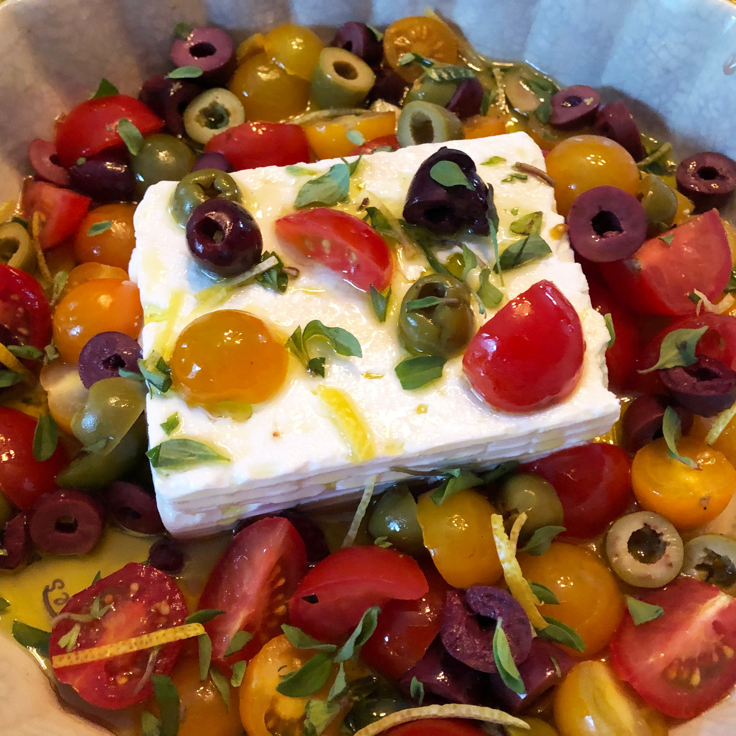 Warm Greek Feta Dip prior to baking. The snow-white slab of Feta is surrounded by olives and grape tomatoes.