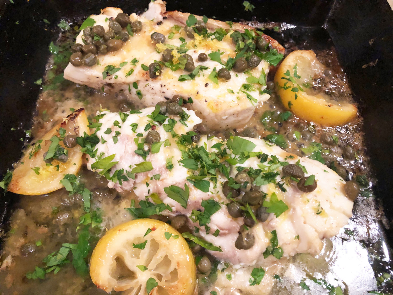 These butter-basted halibut fillets are garnished with capers, lemon zest and minced fresh parsley.