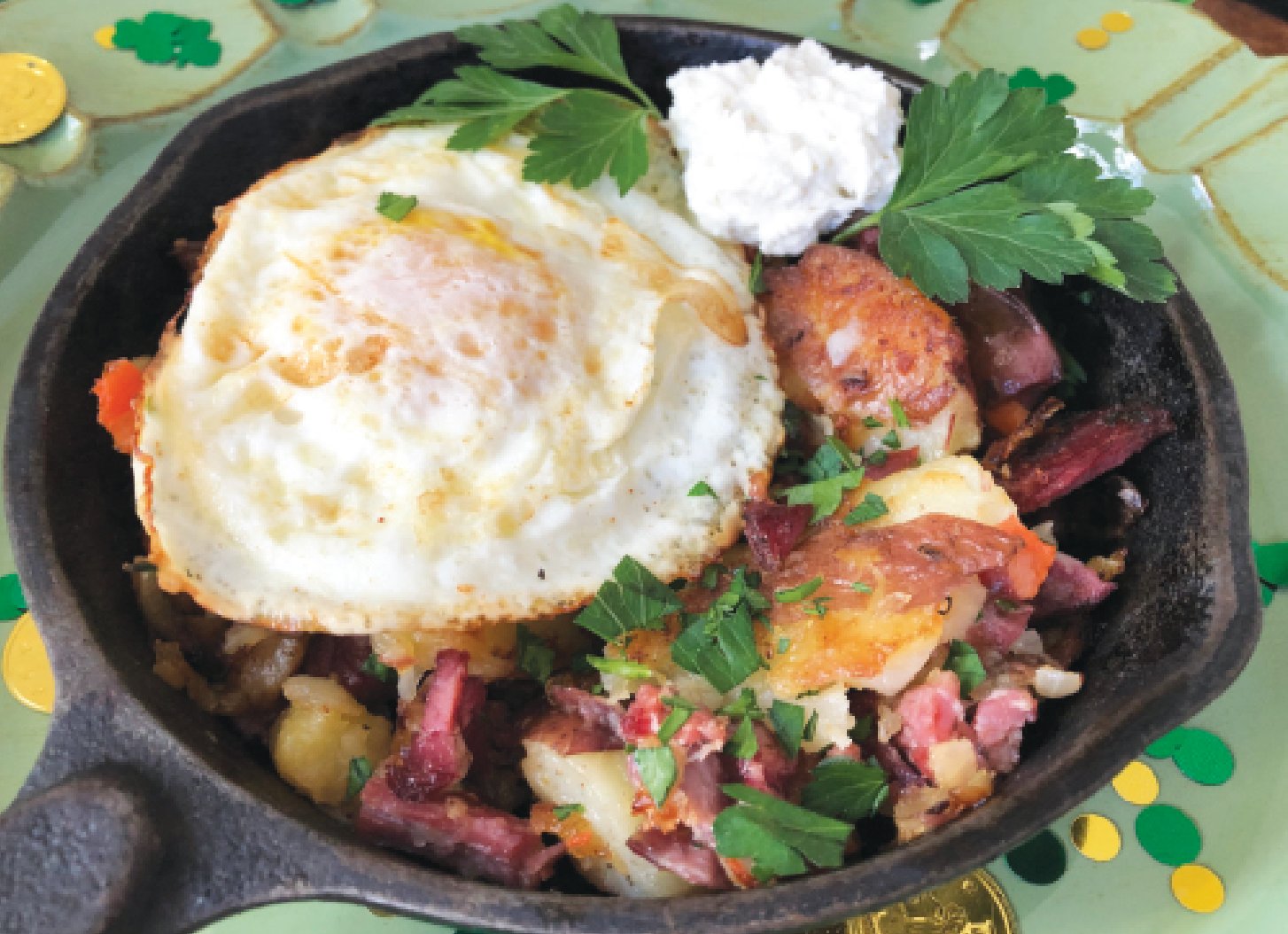 Smashed potatoes serve as the base of this corned beef hash topped by a fried egg and accompanied by a dollop of fresh horseradish sauce.