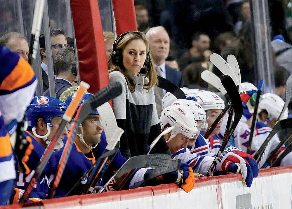 Post-Olympics, A.J. Mleczko has become a color analyst for ESPN and the New York Islanders. Here she stands between the benches of the Islanders and New York Rangers, watching the game and providing commentary.