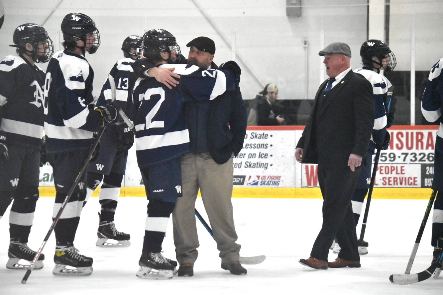 Soren Edwardes (22) and assistant coach Ray Patrick hug after Saturday's game against Sandwich.