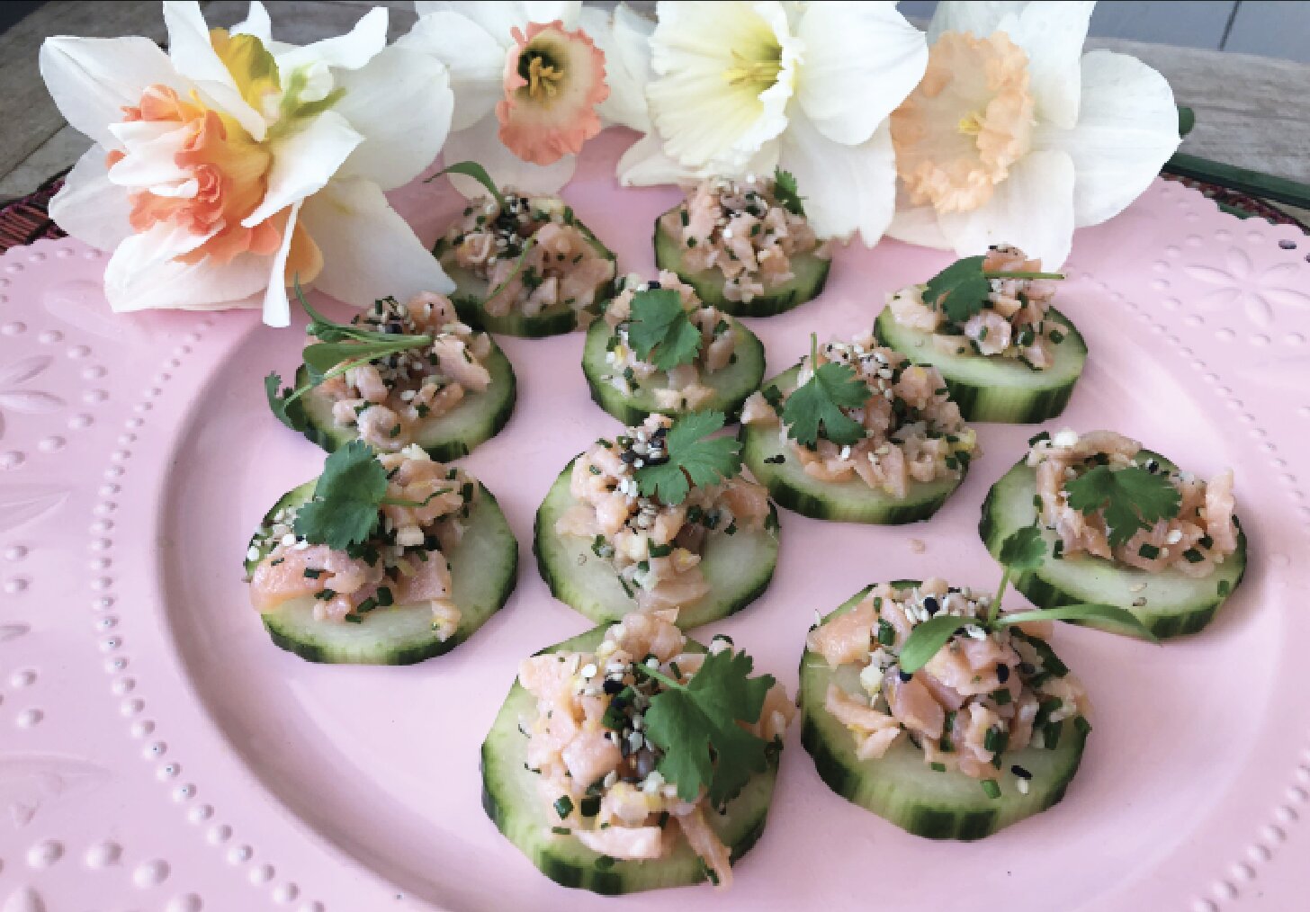 Smoked Salmon Tartare, served on cucumber rounds with sprigs of cilantro.